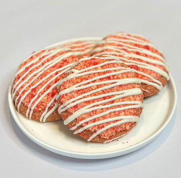 Four Berry Dramatic strawberry crunch cookies topped with white chocolate drizzle and homemade strawberry crunch crumble on a white plate