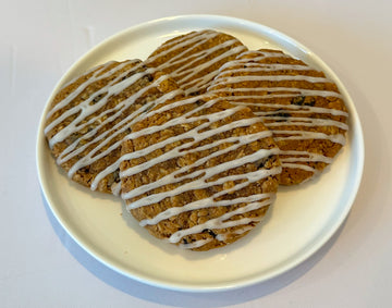 Four Sweet Oat Sensation oatmeal cookies with vanilla icing drizzle on a white plate. 
